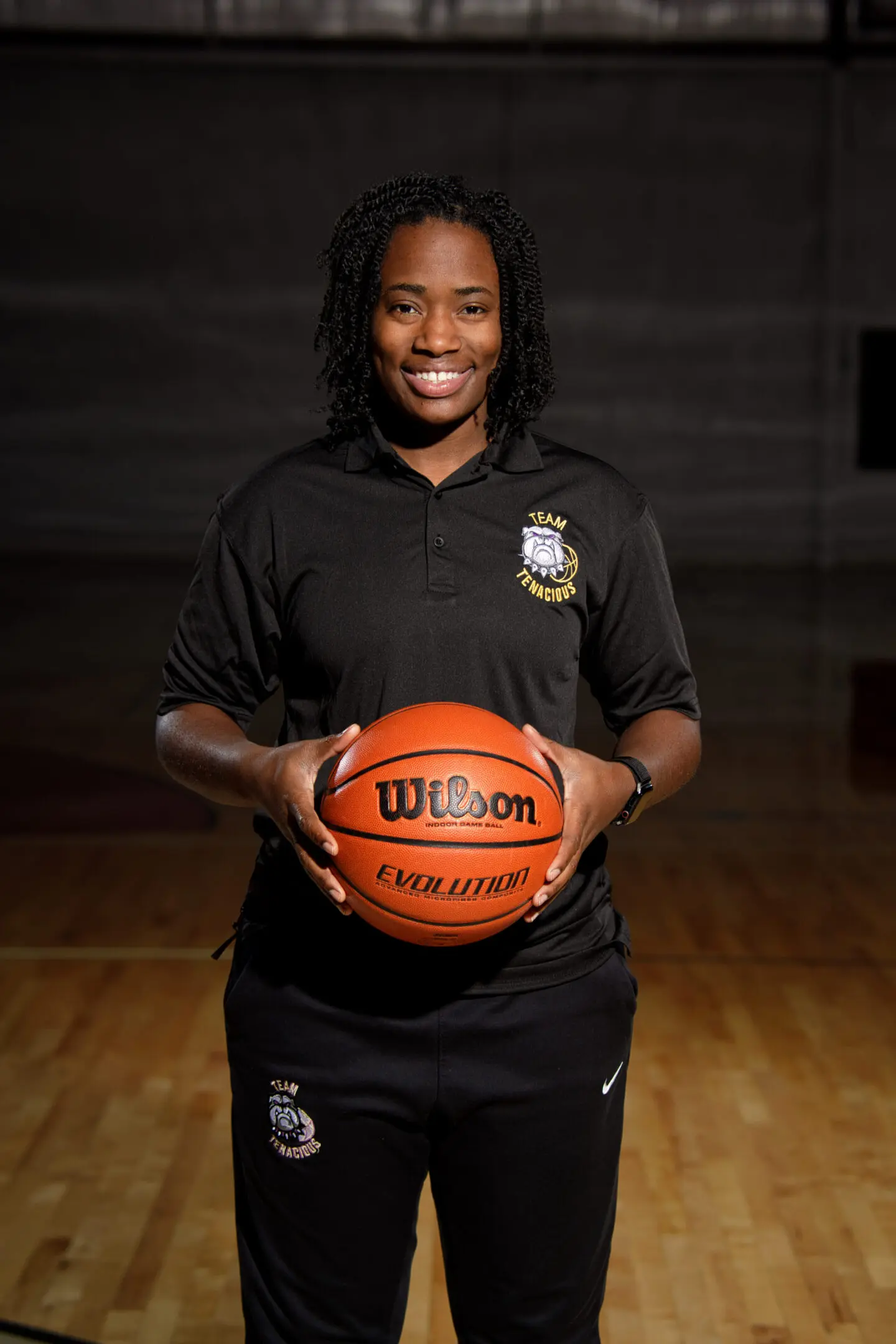 A woman holding a basketball in front of a wall.