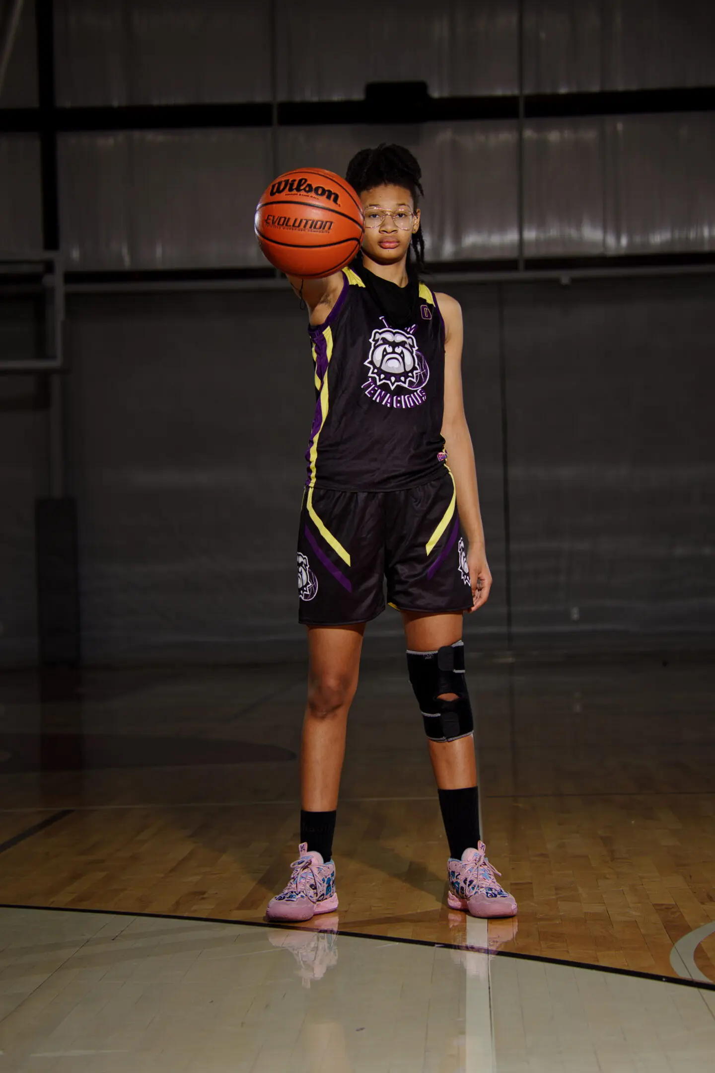 A young girl holding onto a basketball in the air.