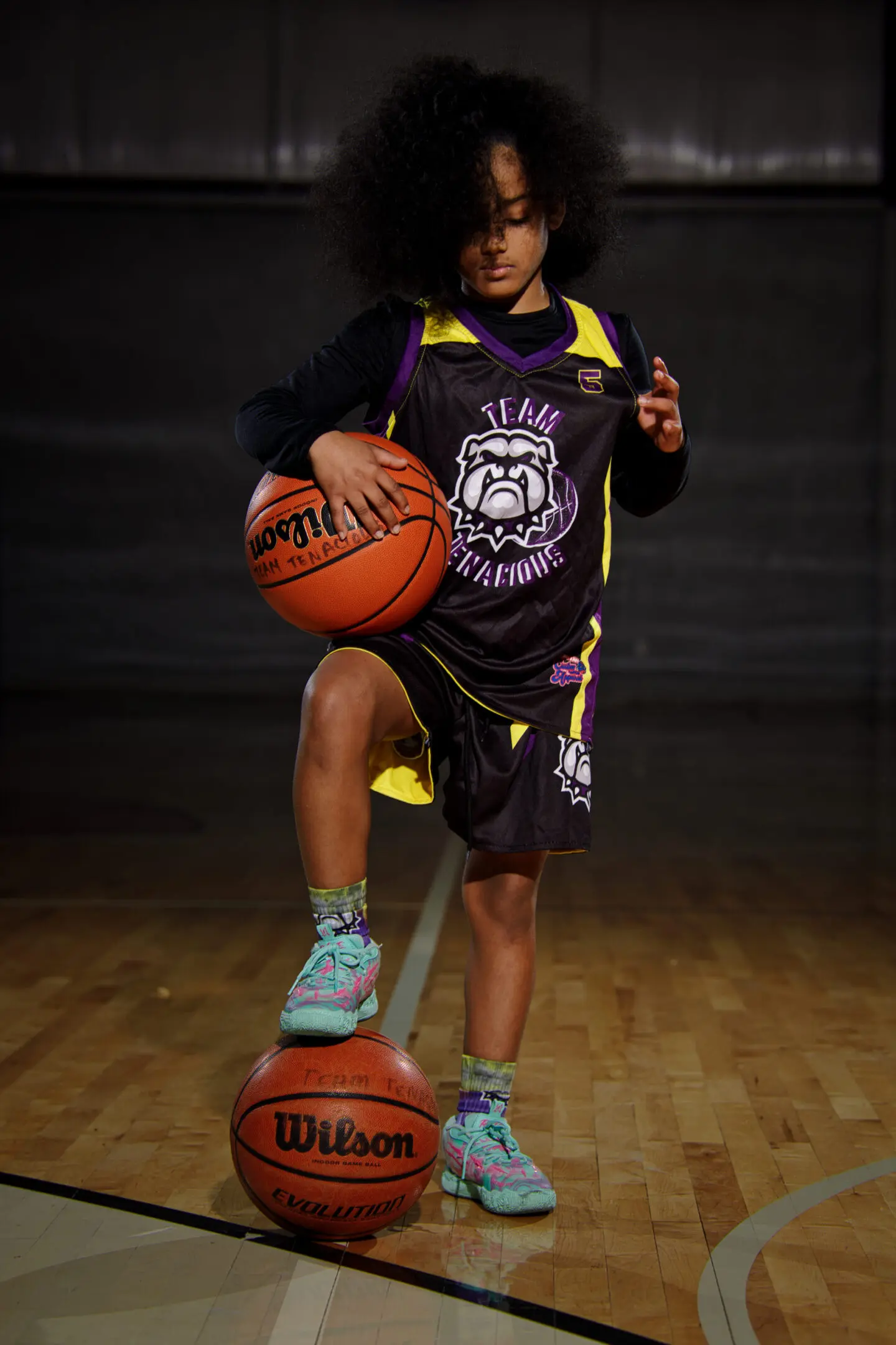 A young man holding onto a basketball on the court