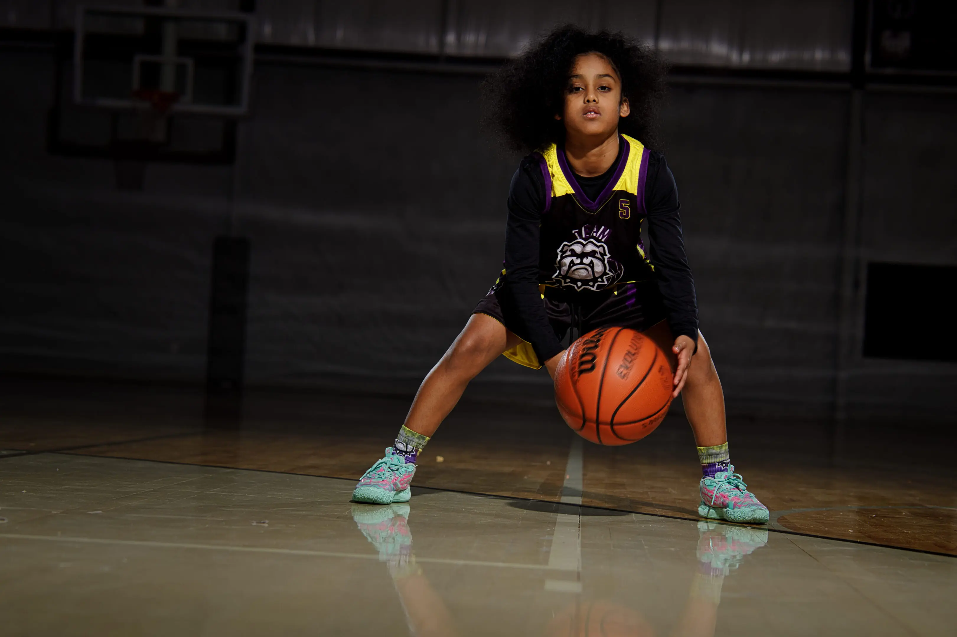 A young girl is holding onto the basketball