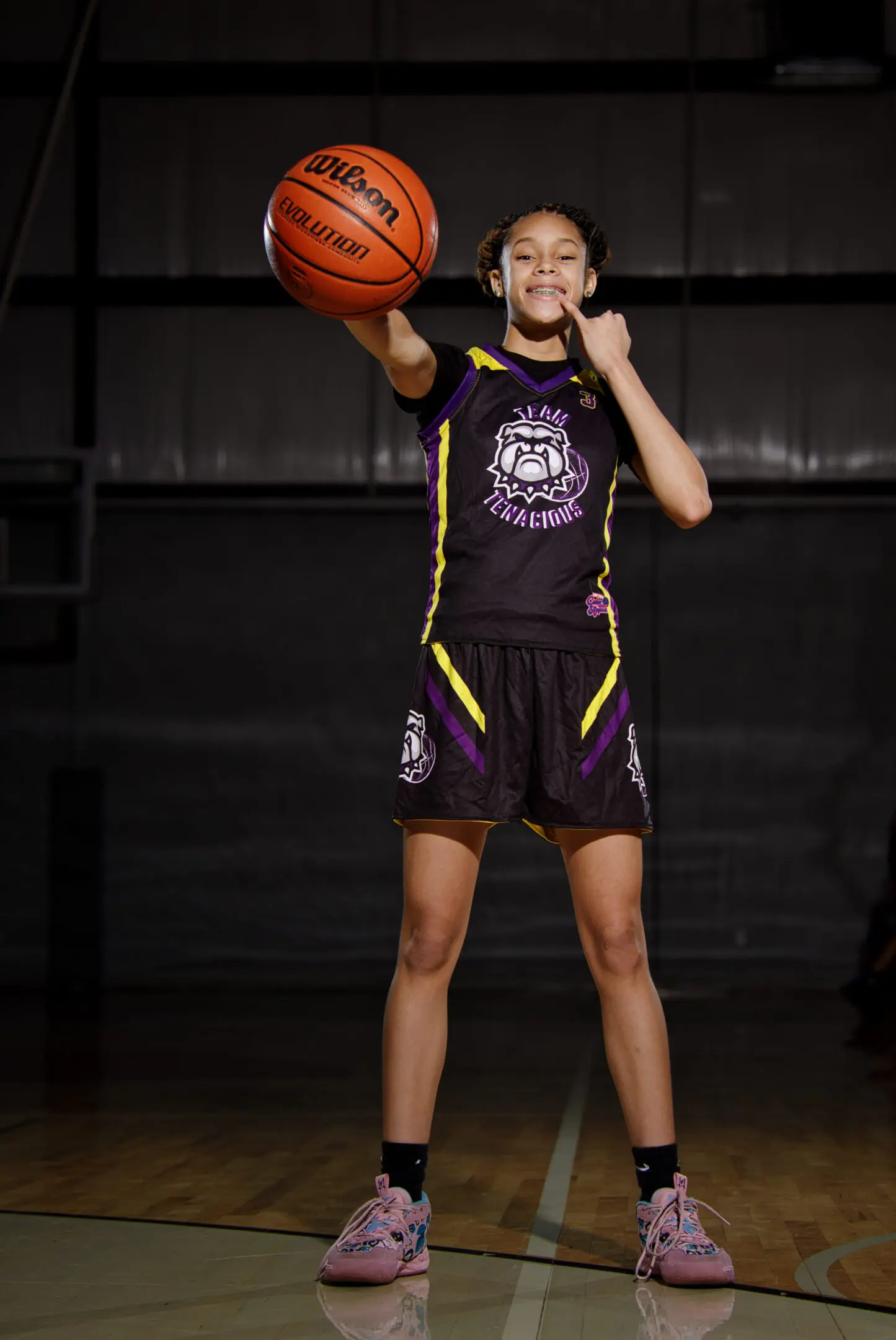 A young girl holding onto a basketball in her hand.