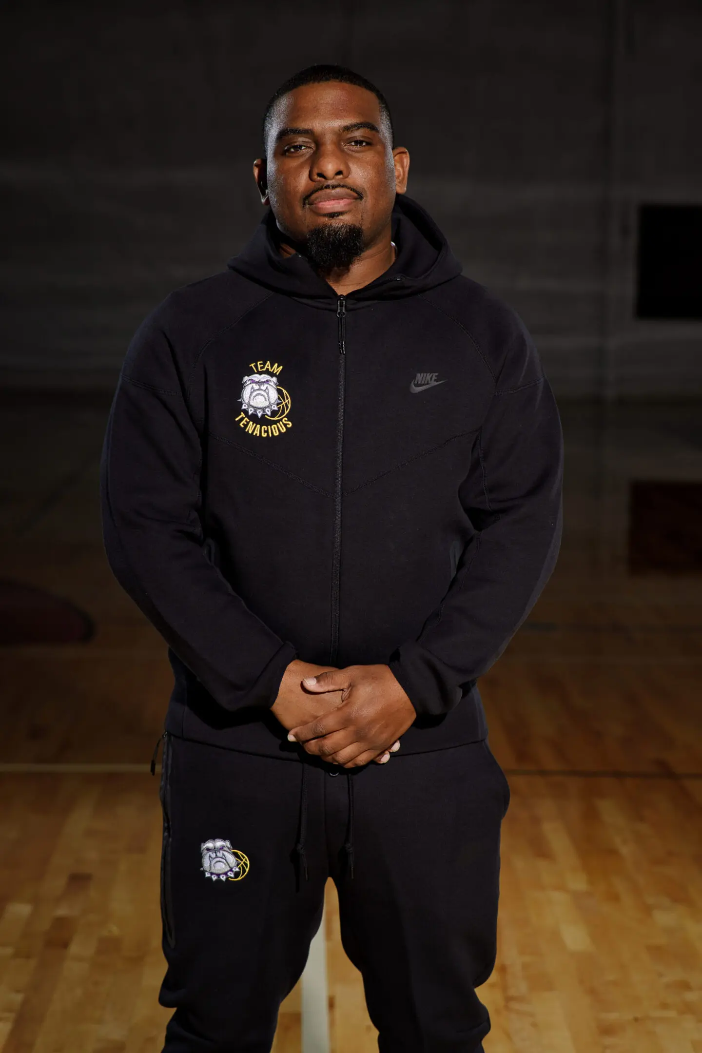 A man in black hoodie standing on a basketball court.